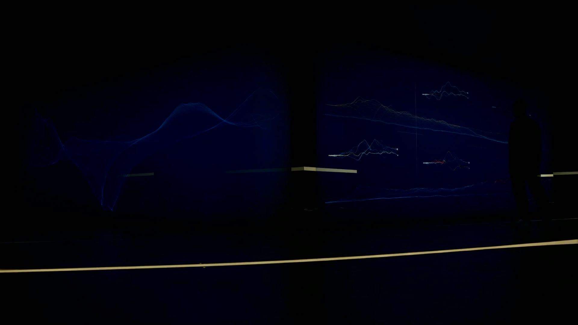 Sala de control en penumbra con paneles de trazabilidad iluminados en azul y una persona supervisando