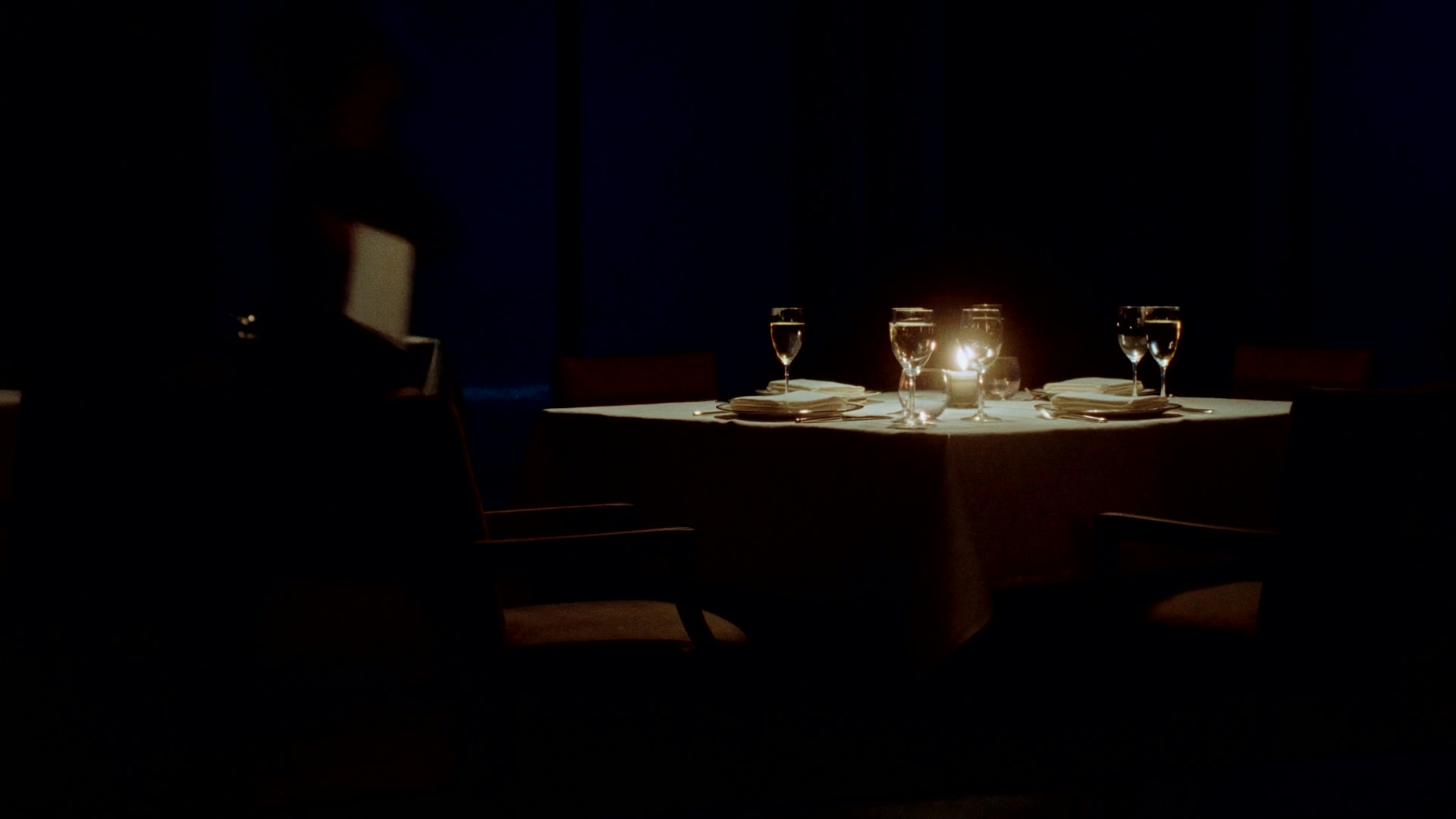 Mesa de restaurante elegante con una silla vacía bajo luz cálida de servicio nocturno